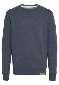 Sudadera de cuello redondo azul, fabricada en tejido de algodón texturizado, con puños y dobladillo acanalados, y una pequeña etiqueta de cuero en la parte inferior izquierda.