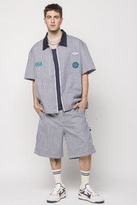 Striped short-sleeve shirt with a navy collar, paired with matching shorts. Additional details include patches and a relaxed fit.