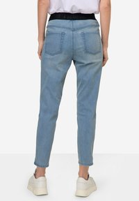 Jeans de mezclilla de color azul claro con una cinturilla elástica negra, diseño de pierna recta y dos bolsillos traseros. Terminados con un dobladillo acampanado.