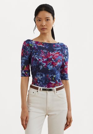 Floral-patterned, fitted top in dark blue with pink, red, and green accents. Features three-quarter sleeves and a wide neckline, paired with white jeans.