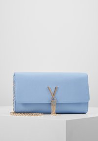 Ljusblå texturerad axelväska med ett guld kedjerem, utrustad med en framträdande V-formad hårdvara och en tofsdetalj.