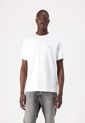 Hvit bomulls t-skjorte med rund hals, korte ermer og en subtil grå logo på brystet; kombinert med lysegrå denimjeans.