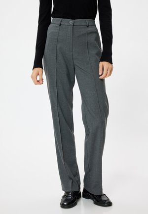 Pantalones ajustados grises de cintura alta, con frente plano, costuras verticales y cierre de botón. Combinados con zapatos negros.