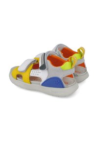 Sandaal colorido con un diseño amarillo, blanco y azul, hecho de tela y goma. Presenta correas de velcro, recortes transpirables y un forro acolchado.