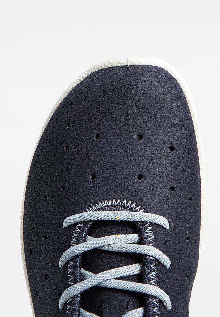 Granatowe trampki z perforowaną cholewką, jasnoniebieskimi sznurówkami i białą gumową podeszwą. Teksturowana powierzchnia i zaokrąglony design nosa.