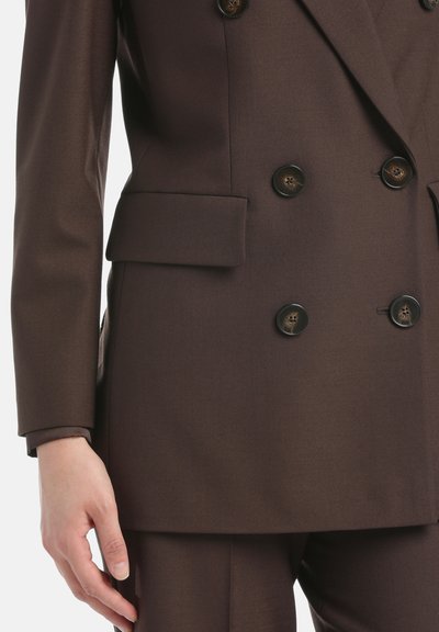 Bruine dubbelzijdige blazer van textuurstof, met grote donkere knopen en een zijzak. Manchetten in een contrasterende tint zichtbaar.
