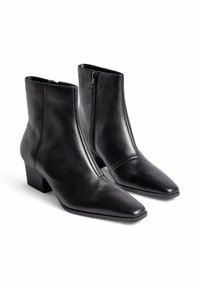 Botas de cuero negras hasta el tobillo con punta afilada, cremallera lateral y un tacón bajo en bloque. Textura suave con un brillo sutil.