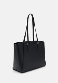 Sac fourre-tout en cuir noir avec deux longues poignées, de forme rectangulaire et avec des coutures minimales, présenté sur un fond blanc uni.