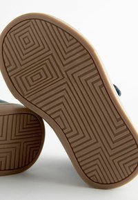Semelle de chaussure en caoutchouc avec un motif texturé comportant des designs géométriques. La couleur est marron avec des variations subtiles de profondeur dans la texture de la surface.