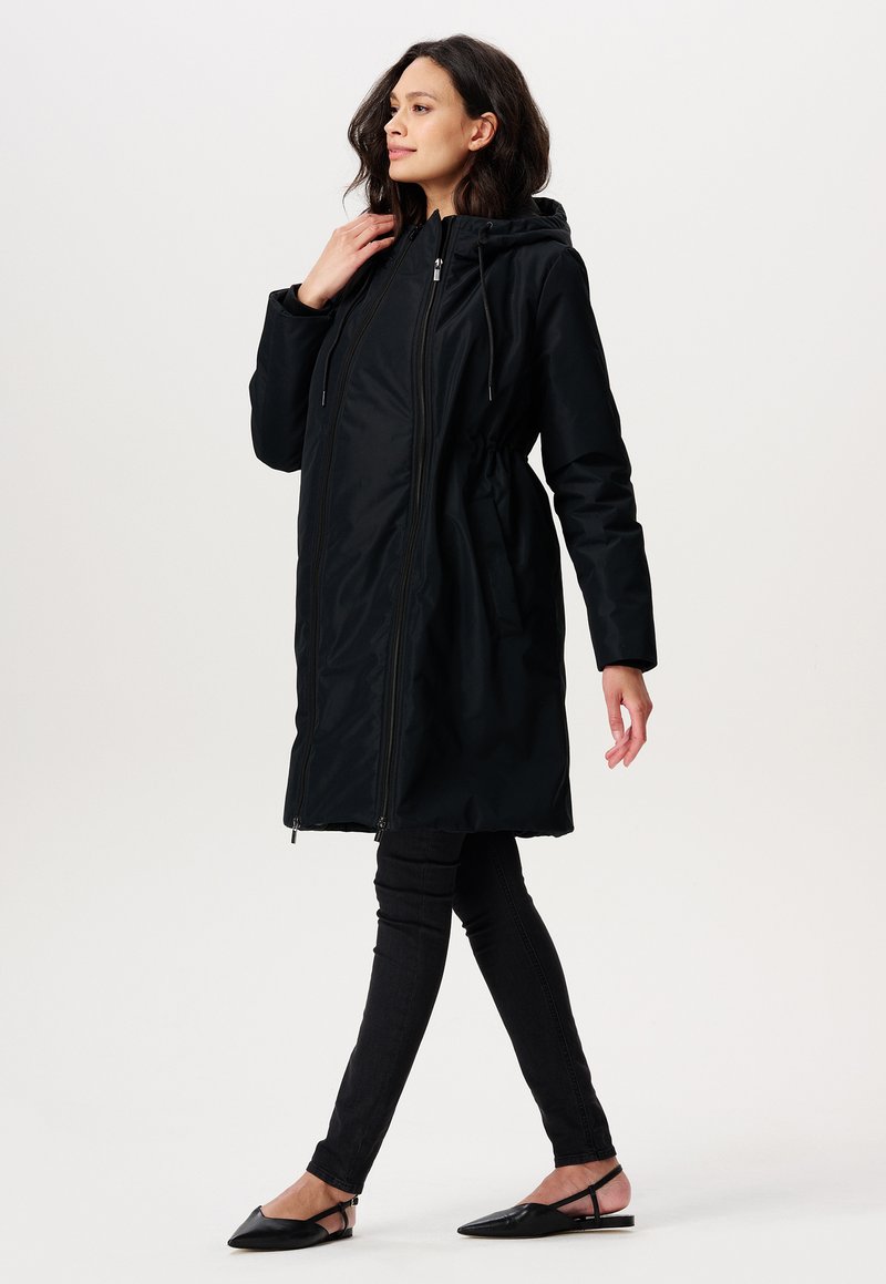 Sorte hættefrakke med elastisk talje, lynlåslukning foran og sidelommer. Glat stof med en let skinnende finish.