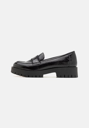 Mocassin en cuir verni noir avec semelle épaisse à rainures et petit talon carré, vue de profil latéral sur fond clair uni.