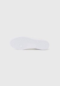 White sneaker outsole with textured grip pattern, featuring a circular accent on the heel and smooth edges for a clean design.