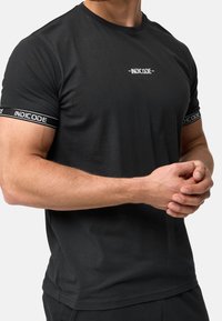 Czarna bawełniana koszulka t-shirt z okrągłym dekoltem i krótkimi rękawami, z logo na piersi i kontrastowym paskiem na rękawach.