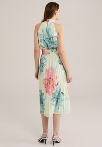 Rochie plisată florală în galben pastelat, cu flori albastre și roz, guler halter, talie elastică și un design fluid de lungime medie.