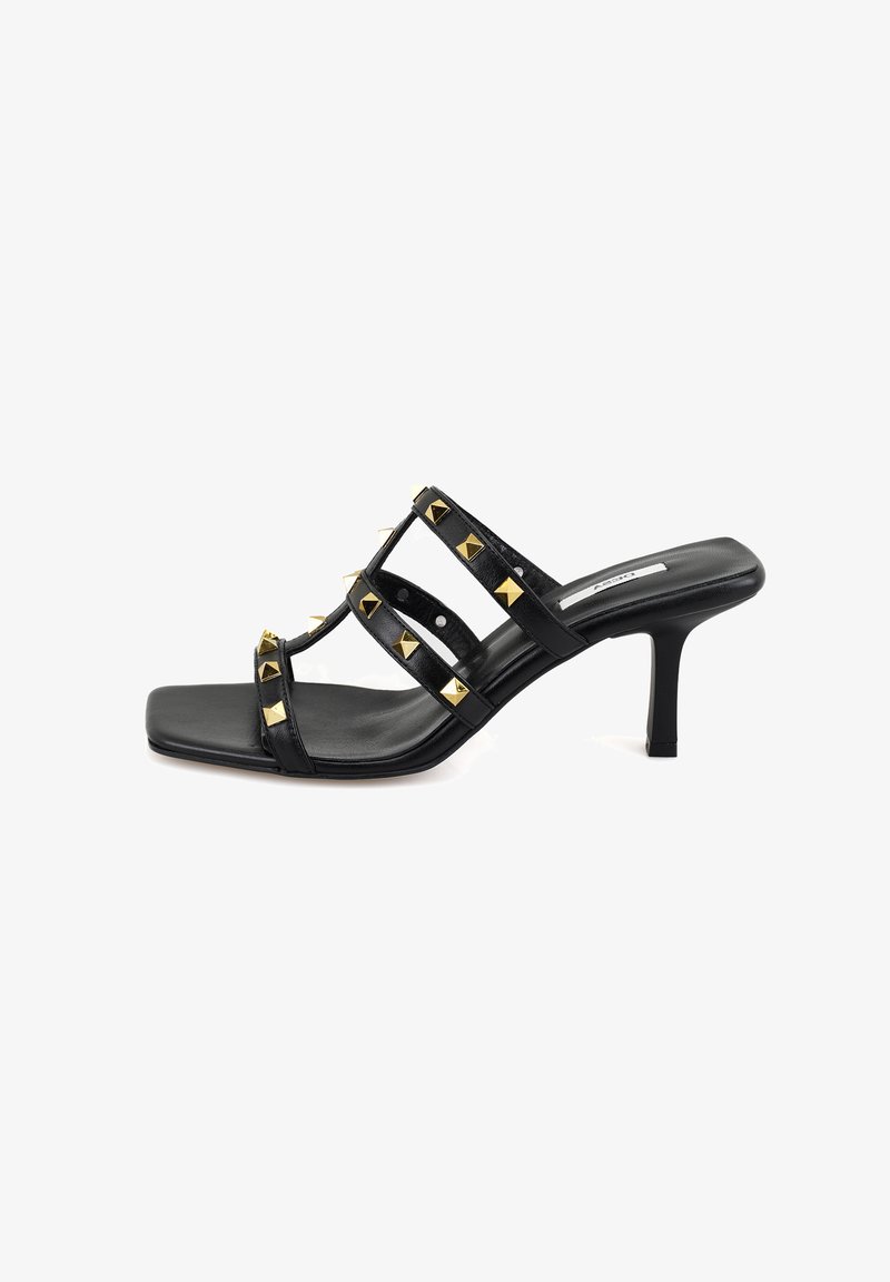 Schwarze High Heels Sandalen mit drei breiten Riemen, die mit goldenen Pyramidennieten verziert sind. Quadratische Zehenpartie und ein schlanker Stiletto-Absatz. Glatte Ledertextur.