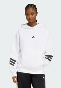 Biely mikina s kapucňou a predným vreckom, čierne logo Adidas na hrudi a tri čierne pruhy na rukáve. Mäkká tkanina, voľný strih a dizajn s kapucňou.