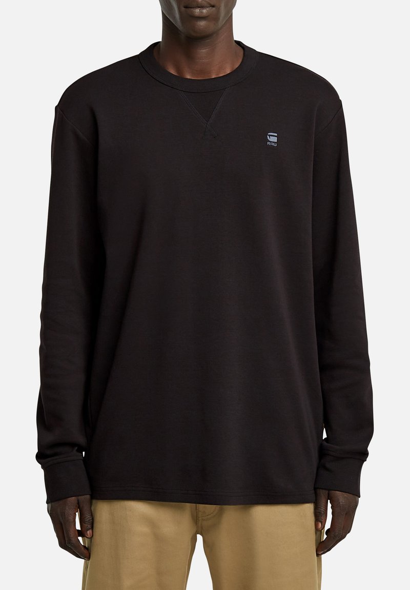 Schwarzer Langarm-Sweatshirt mit Rundhalsausschnitt, gerippten Bündchen und einem kleinen Logo auf der Brust. Glatte Textur und lockere Passform.