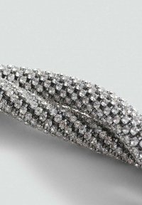 Zilveren armband met meerdere rijen sprankelende strass in een rasterpatroon, met een gladde metalen basistextuur.