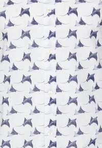 Biała koszula na guziki z wzorem ciemnoniebieskich i jasnoniebieskich płaszczek. Materiał wydaje się lekki i teksturowany, z delikatnym połyskiem.