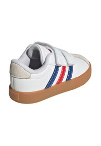Zapatilla blanca con rayas rojas y azules, parte superior de cuero, correas de velcro, suela de goma y un suave acento gris en el talón.