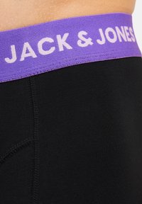 Mustat boxer-pöksyt, joissa on violetti elastinen vyötärö, jossa lukee valkoisella tekstillä "JACK & JONES". Suora pinta ja istuva muotoilu.