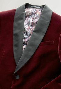 Głęboki burgundowy aksamitny żakiet smokingowy z czarnym satynowym klapą i wzorzystą jedwabną podszewką z motywami kwiatowymi i paisley.