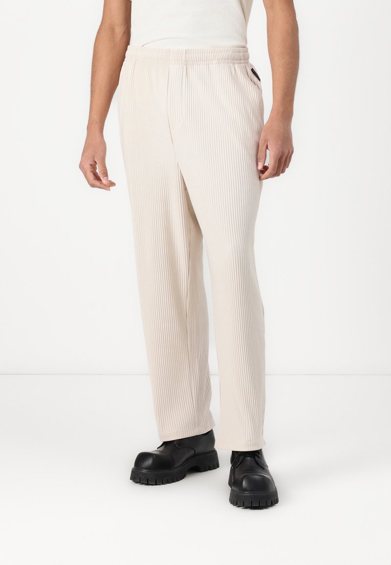 Beige geribde broeken met een elastische tailleband, zijzakken, rechte pijpen en een zachte textuur, gecombineerd met zwarte chunky schoenen.