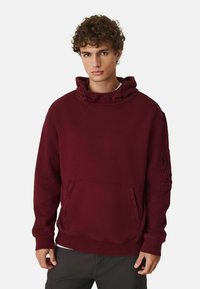 Bordeaux hoodie met een hoge hals, voorzak en zijzak met rits. Gemaakt van zachte stof met een relaxte pasvorm en geribbelde manchetten.