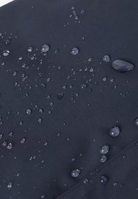 Vedeneristävä kangas syvässä laivastonsinisessä värissä, jossa on teksturoitu pinta; vedenpisaroita näkyy materiaalilla, mikä korostaa sen vedenpitävää laatua.