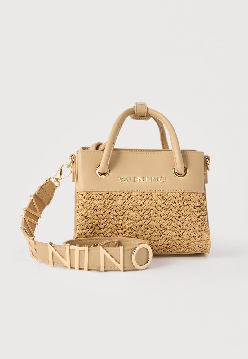 Μπεζ τσάντα Valentino με πλεκτό κάτω μέρος, λείο πάνω τμήμα, δύο λαβές και αποσπώμενο ιμάντα που σχηματίζει τη λέξη "VALENTINO" με μεγάλα γράμματα.