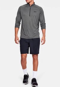 Gray long-sleeve zip-up top made of a textured fabric, paired with navy shorts. Black sneakers and white socks complete the outfit.