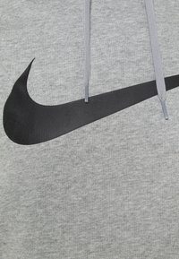 Grijze hoodie met een zachte textuur, voorzien van een groot zwart Nike-logo. Lichte grijze trekkoorden maken het ontwerp af.