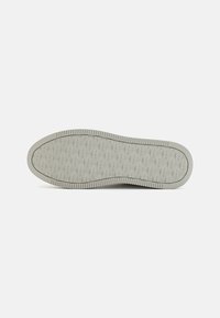 Suola di una scarpa, materiale in gomma grigio chiaro, strutturata con un motivo a diamante, con bordi rigidi per trazione e supporto.