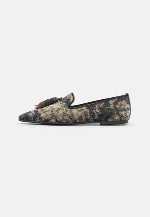 Chaussure slip-on avec motif floral en velours foncé et pompons marron sur une semelle plate, montrée de profil sur un fond uni.