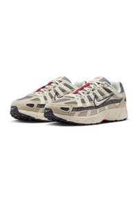 Beige and gray mesh sneakers with red accents, featuring a rounded toe, textured suede panels, and a durable black rubber outsole.