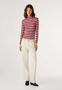 Gestreepte rode en witte fitted turtleneck-top, gecombineerd met witte wijde-pijpenbroek en zwarte enkellaarsjes met hak. Soepele textuur, geribbelde uitvoering.