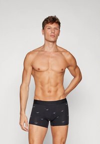 Svarta boxerbriefs med resår i midjan med logotyp. Tyget är slätt med ett subtilt mönster av små grå fåglar. Passformen är tajt och framhäver kroppens form.