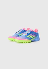 Blaue und rosa Fußballschuhe mit texturiertem Finish, grüner Gummisohle und mehrfarbigen Schnürsenkeln. Verfügt über dezente Markenkennzeichnung und Grippdetails.