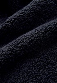 Tmavě námořnická modrá, měkká tkanina s hebkým, strukturovaným povrchem a vlnitým vzorem. Materiál vypadá silně a útulně.
