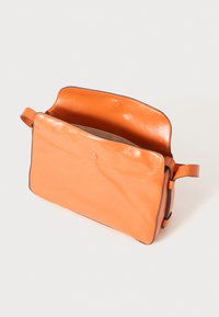 Oranž nahast kott, millel on sile tekstuur, ristküliku kujuline ja avatud ülemine osa. Omab ühte sang ja minimalistlikku disaini.