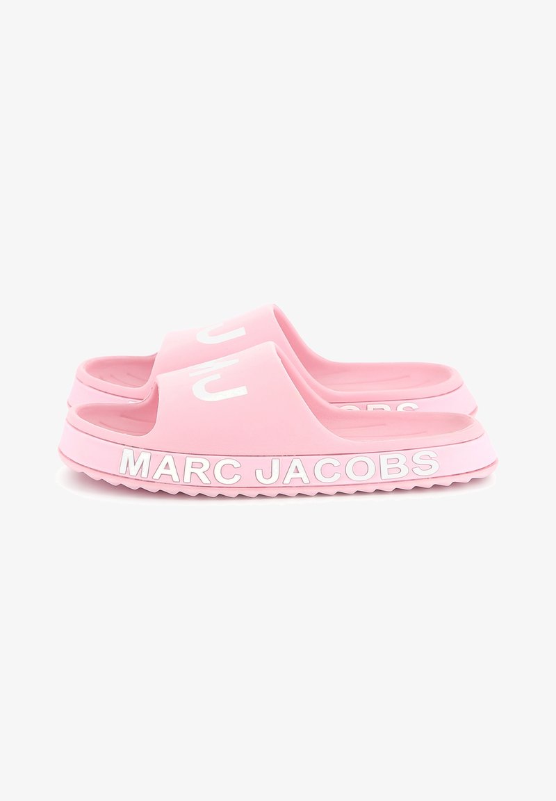 Pink rubber slides yang memiliki strap lebar, desain open toe, dan teks terukir putih "MARC JACOBS" di sepanjang sol. Outsole tekstur untuk daya cengkeram.