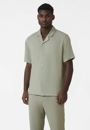 Lysegrøn kortærmet skjorte med knapper, lavet af et tekstureret stof, med en hakkrave og en løs pasform, kombineret med matchende bukser.