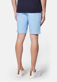 Jasnoniebieskie bawełniane szorty o prostym kroju, sięgające do połowy uda, połączone z białymi trampkami z brązowymi akcentami.