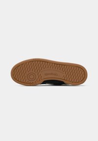 Čierna podrážka sneakers s textúrovanou gumou, ktorá má diamantom vzor, logo a kontrastný béžový medzipodrážku pre lepšiu priľnavosť a odolnosť.