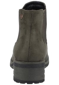 Vihreä samettinen nilkkabotti, jossa on paksu musta pohja, pienen metallikoristeen kera kantapäässä ja sileä sisävuori, esittelee virtaviivaista muotoilua.