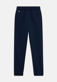 Pantalon de survêtement bleu marine en tissu doux, avec une taille élastique, des chevilles resserrées et un petit logo Lacoste sur la cuisse gauche.