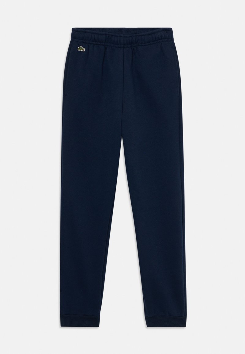 Pantalon de survêtement bleu marine en tissu doux, avec une taille élastique, des chevilles resserrées et un petit logo Lacoste sur la cuisse gauche.