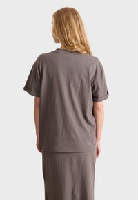 Gray cotton t-shirt with short sleeves, rolled cuffs, and a relaxed fit. The back features a smooth, unembellished surface.
