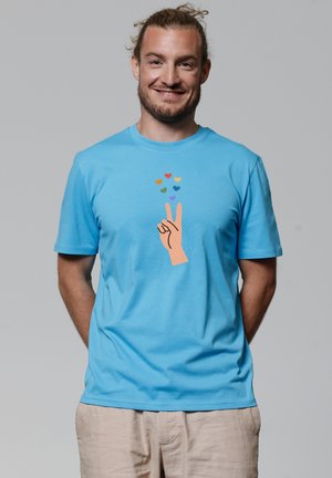 Lichtblauw katoenen t-shirt met een afbeelding van een hand die een vredesteken maakt, omringd door kleurrijke harten. Zachte structuur, casual pasvorm.