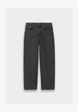 Juodi tiesūs džinsai su penkiais kišeniais, mygtuko užsegimu ir matomu siuvimu, išdėstyti ant neutralios spalvos fono.